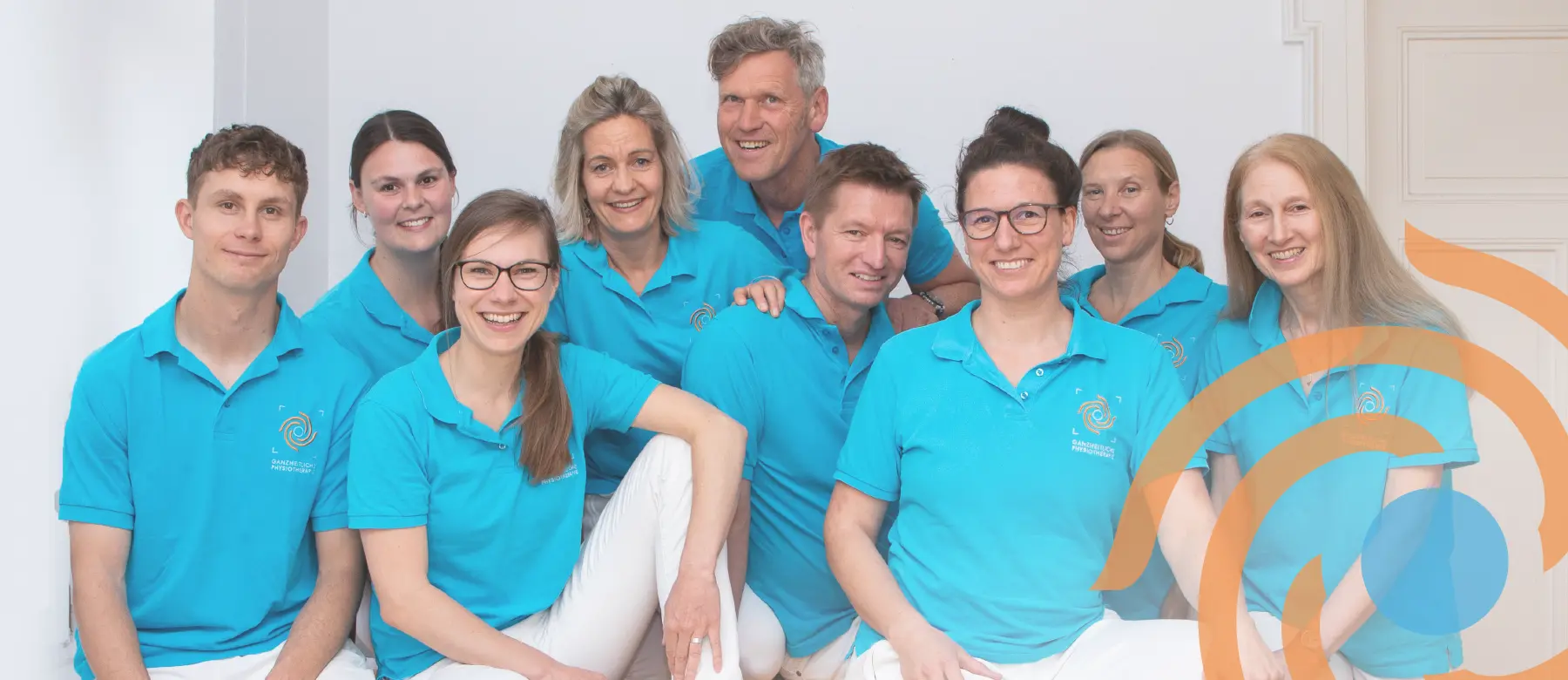 Gruppenfoto vom Therapeuten-Team. Alle tragen das gleiche Poloshirt in Blau mit dem gestickten Logo auf der Brust.